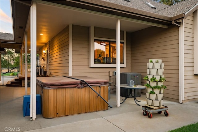 patio terrace at dusk featuring a hot tub and central air condition unit