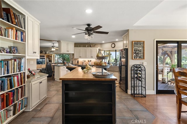 kitchen with black fridge, a wealth of natural light, wood-type flooring, and a kitchen island