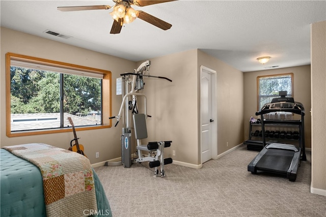 bedroom with ceiling fan, light carpet, and a textured ceiling