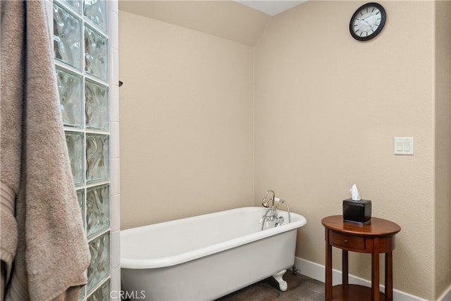 bathroom featuring vaulted ceiling and a tub