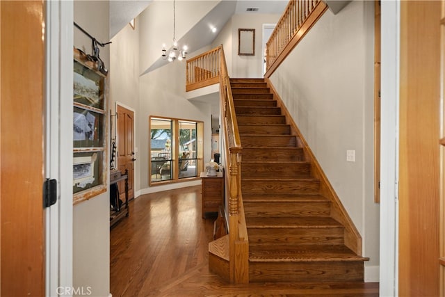 stairway featuring a notable chandelier, a high ceiling, and hardwood / wood-style floors