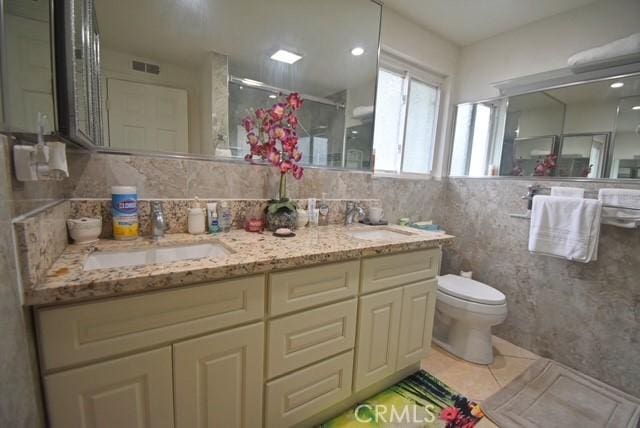 bathroom featuring vanity, a shower with shower door, tile walls, and toilet