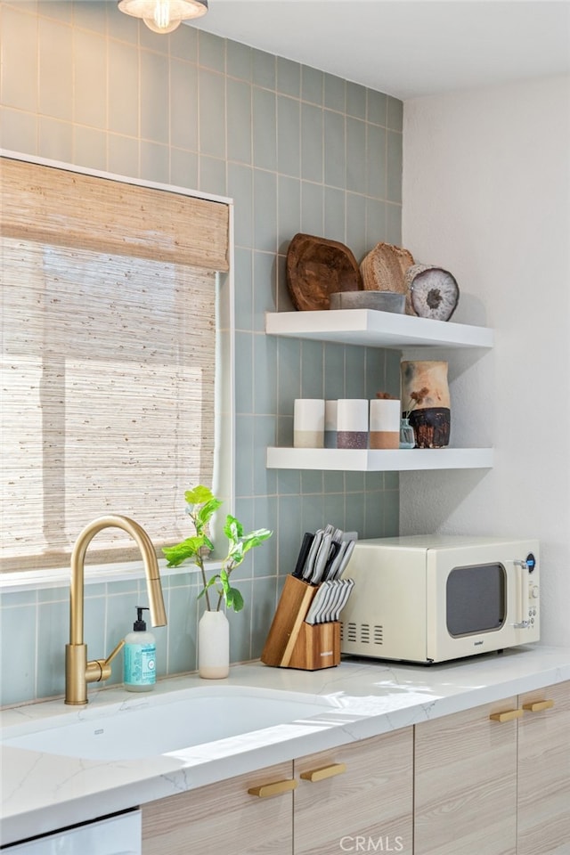 details featuring light brown cabinetry, light stone countertops, sink, and white appliances