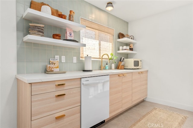 kitchen featuring decorative backsplash, white appliances, light brown cabinetry, and sink