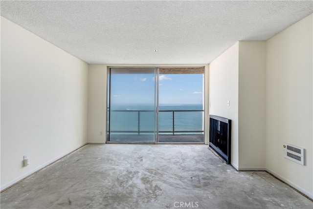 unfurnished living room with concrete floors, a water view, and a textured ceiling