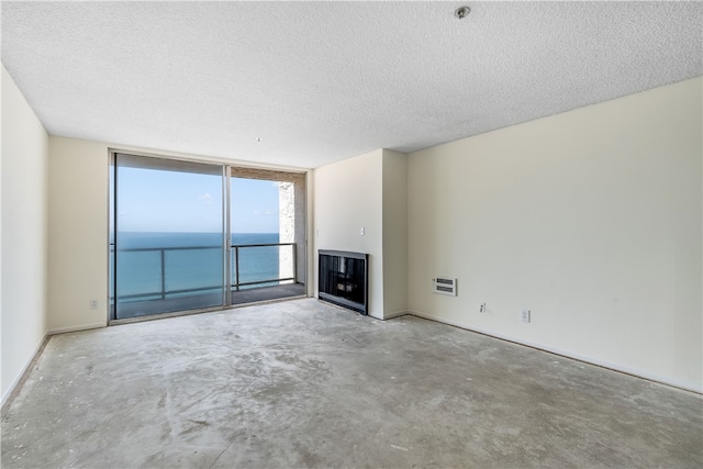 unfurnished living room featuring a textured ceiling, a water view, a multi sided fireplace, and concrete floors