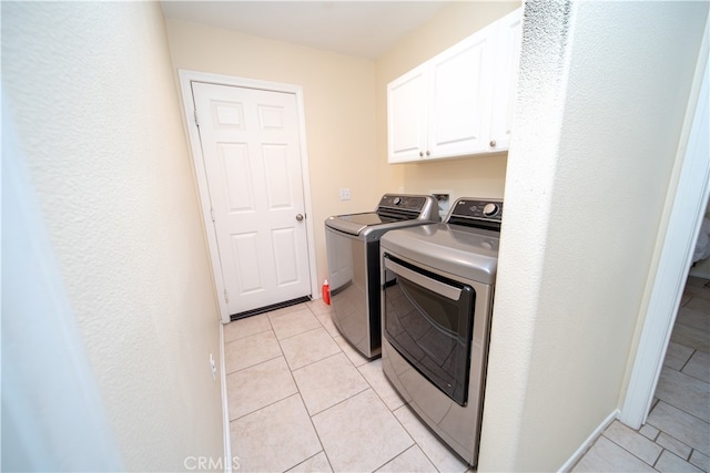 washroom featuring washer and clothes dryer, light tile patterned floors, and cabinets