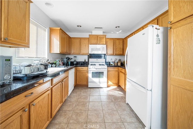 kitchen featuring white appliances, light tile patterned floors, and dark stone counters