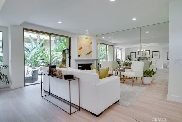 living room with light wood-type flooring, a fireplace, a wealth of natural light, and recessed lighting