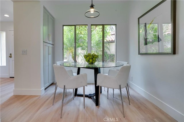 dining room with a wealth of natural light, baseboards, and light wood-style flooring