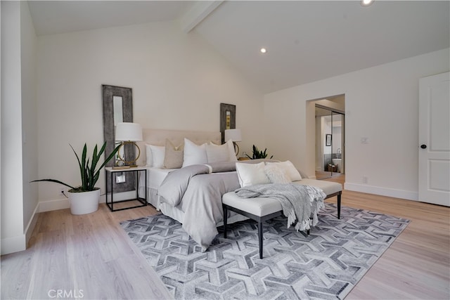 bedroom with light wood-type flooring, lofted ceiling with beams, and a closet