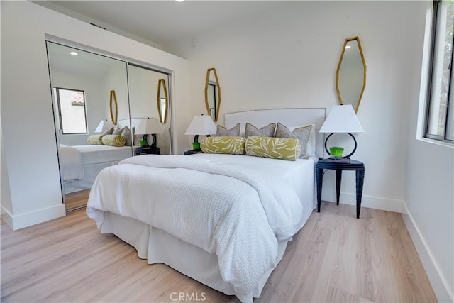 bedroom with baseboards, wood finished floors, recessed lighting, and a closet