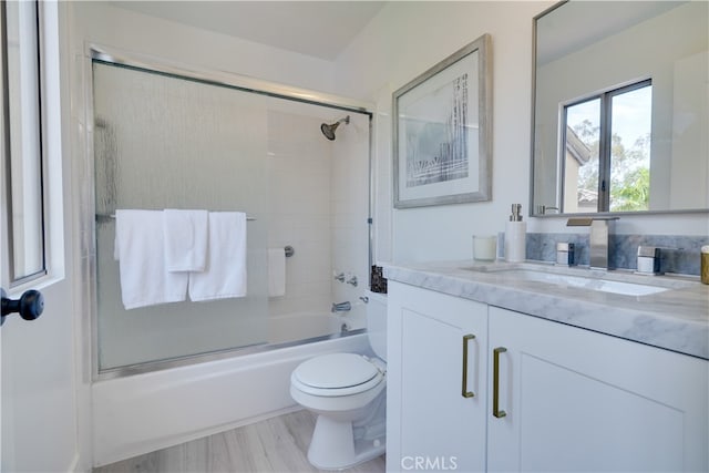 full bathroom with hardwood / wood-style floors, toilet, vanity, and enclosed tub / shower combo