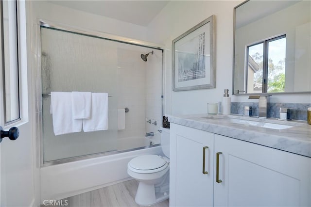 full bathroom with combined bath / shower with glass door, vanity, and toilet