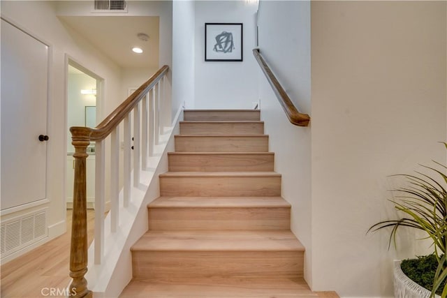 stairway featuring recessed lighting, wood finished floors, and visible vents