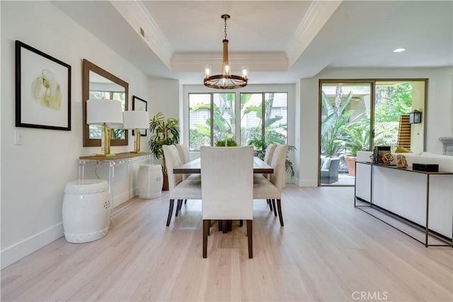dining room with light wood-style floors, a wealth of natural light, ornamental molding, and an inviting chandelier