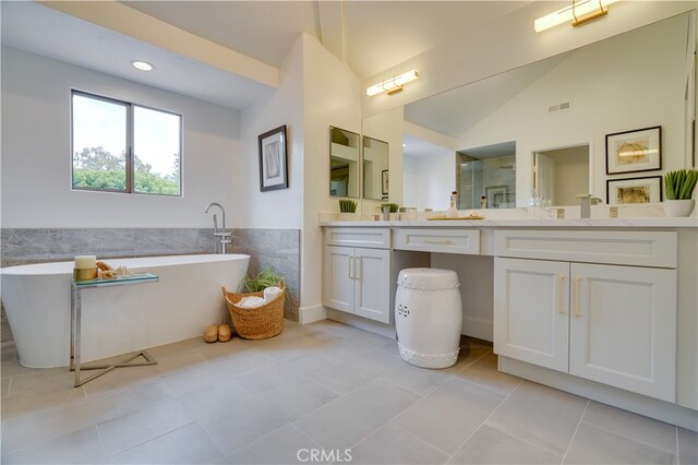 bathroom featuring lofted ceiling, a bath, tile patterned flooring, and vanity