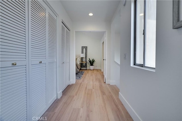 hallway featuring baseboards, recessed lighting, and light wood-style floors
