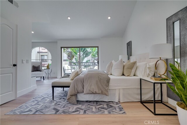 bedroom with light wood-type flooring, access to exterior, and lofted ceiling