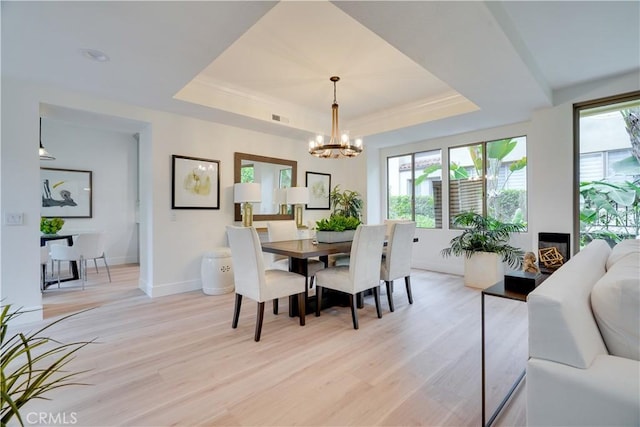 dining room with an inviting chandelier, a tray ceiling, visible vents, light wood-style floors, and baseboards