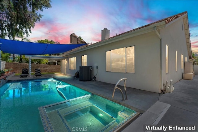 pool at dusk with an in ground hot tub, cooling unit, and a patio