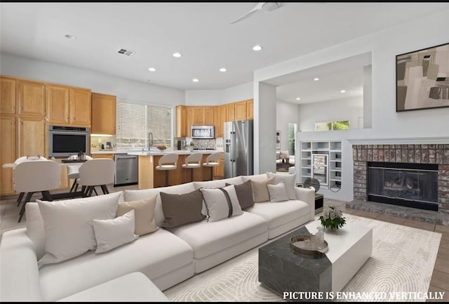 living room featuring a fireplace, light hardwood / wood-style flooring, and sink