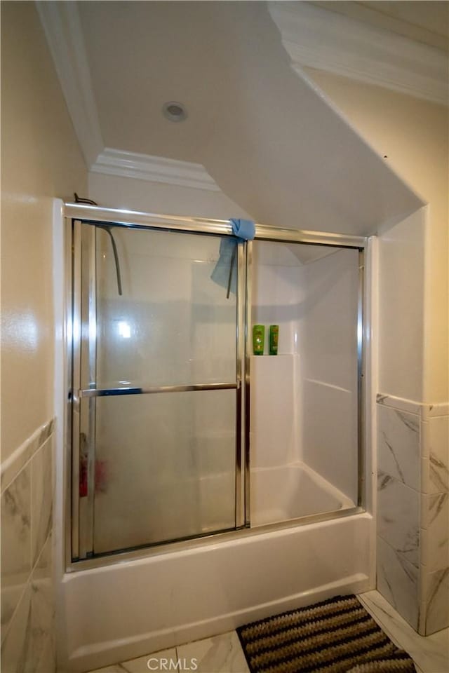 full bath featuring tile walls, ornamental molding, bath / shower combo with glass door, and a wainscoted wall