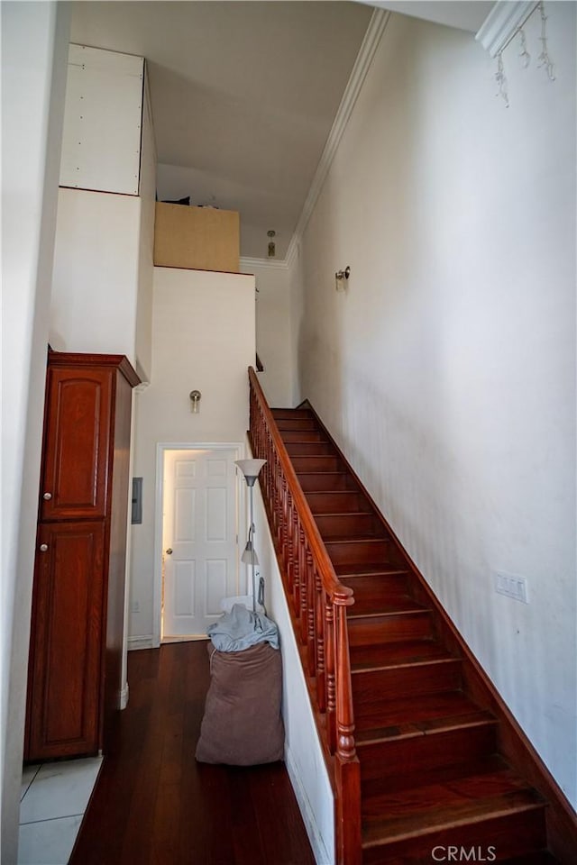 stairs with crown molding, baseboards, and wood finished floors