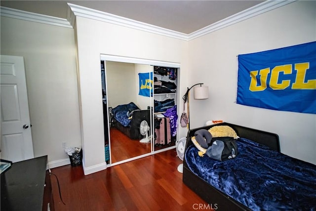bedroom featuring baseboards, ornamental molding, a closet, and wood finished floors