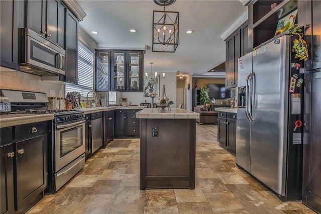 kitchen with decorative light fixtures, a kitchen island, an inviting chandelier, stainless steel appliances, and dark brown cabinets