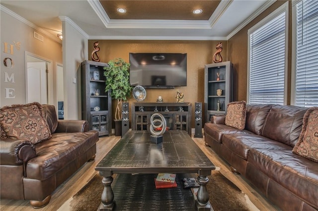 living room with ornamental molding, a raised ceiling, and light hardwood / wood-style flooring