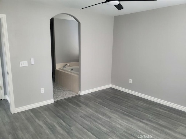 unfurnished bedroom with ceiling fan and dark wood-type flooring