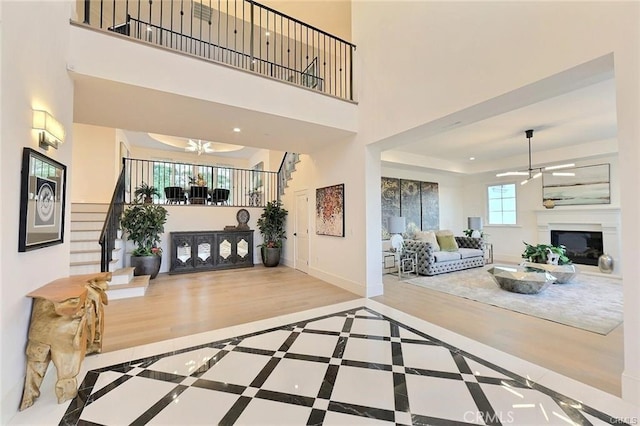 20487 Gartel Dr, Walnut, CA 91789 - foyer entrance featuring ceiling fan, stairs, a glass covered fireplace, a high ceiling, and wood finished floors