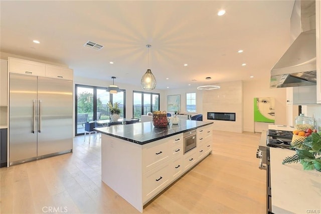 20487 Gartel Dr, Walnut, CA 91789 - kitchen with stainless steel appliances, wall chimney range hood, white cabinets, light wood finished floors, and plenty of natural light