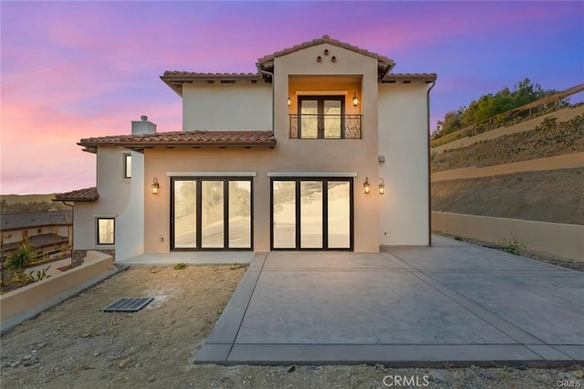 20487 Gartel Dr, Walnut, CA 91789 - back of house at dusk with a tiled roof, a chimney, stucco siding, and a balcony