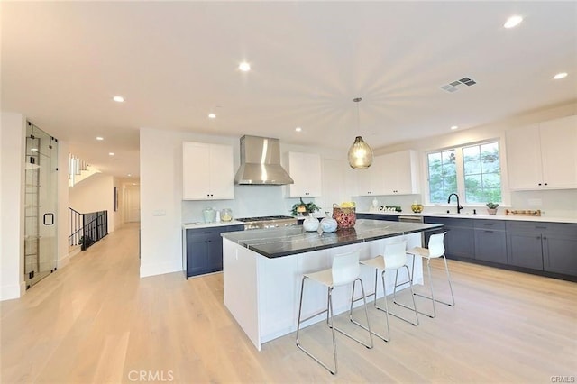 20487 Gartel Dr, Walnut, CA 91789 - kitchen featuring wall chimney exhaust hood, a breakfast bar, a center island, light wood-type flooring, and white cabinets