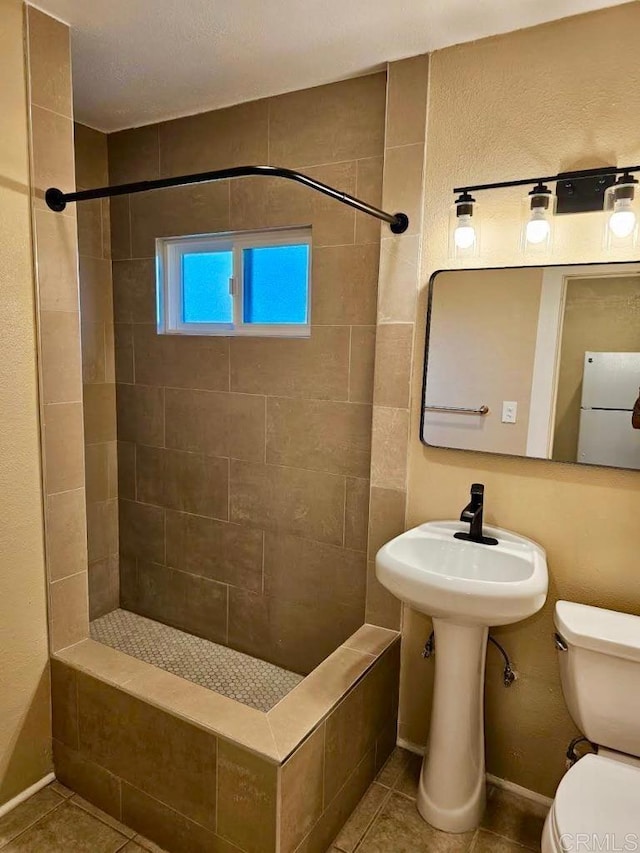 bathroom with tile patterned flooring, toilet, and tiled shower