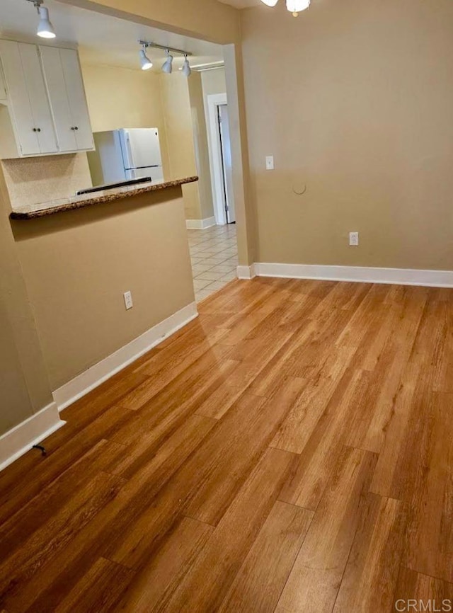 empty room with light wood-type flooring and rail lighting