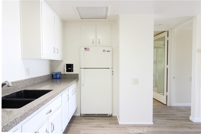 kitchen featuring white cabinets, sink, light wood-type flooring, and white fridge