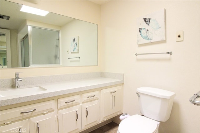 bathroom featuring vanity, a shower with shower door, and toilet