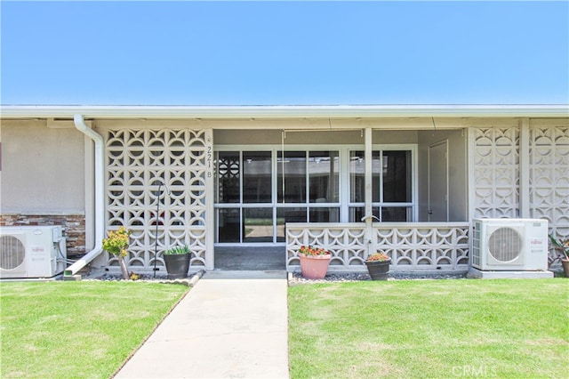 view of exterior entry featuring ac unit and a yard