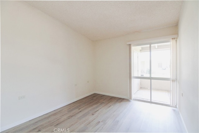 spare room with a textured ceiling and light hardwood / wood-style flooring