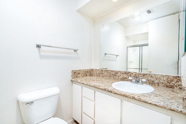 bathroom with vanity, toilet, and a shower with shower door