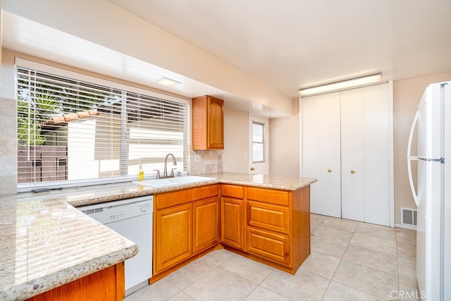 kitchen featuring light tile patterned flooring, kitchen peninsula, sink, white appliances, and decorative backsplash