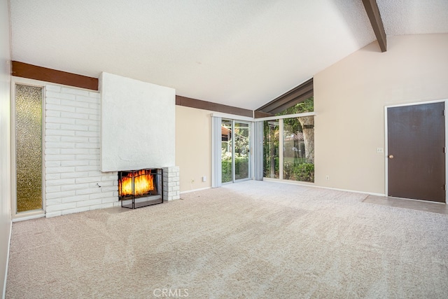 unfurnished living room with lofted ceiling with beams, a brick fireplace, and carpet