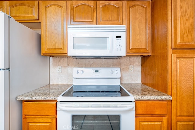 kitchen with white appliances, light stone counters, and tasteful backsplash