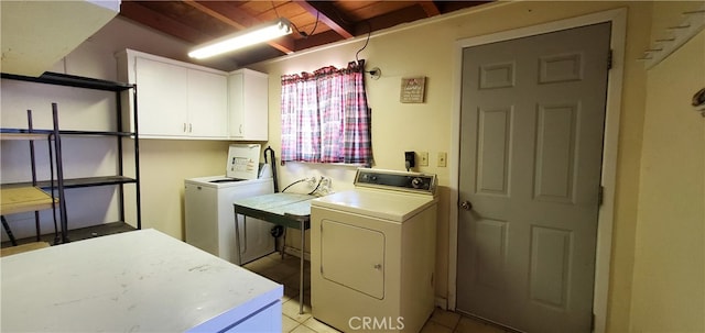 washroom with cabinets, washing machine and dryer, and light tile patterned floors