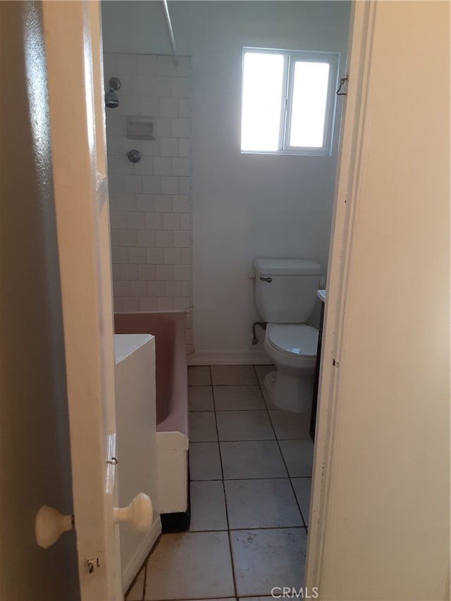 bathroom with toilet, tiled shower / bath, and tile patterned flooring