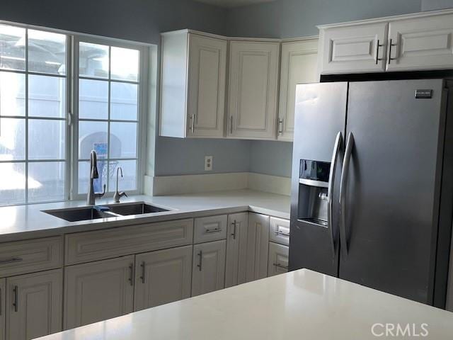 kitchen with stainless steel fridge with ice dispenser, white cabinets, and sink