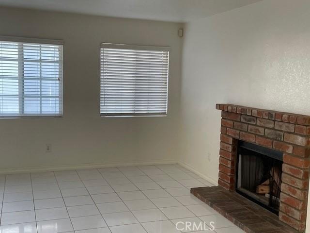 unfurnished living room with a brick fireplace and light tile patterned floors